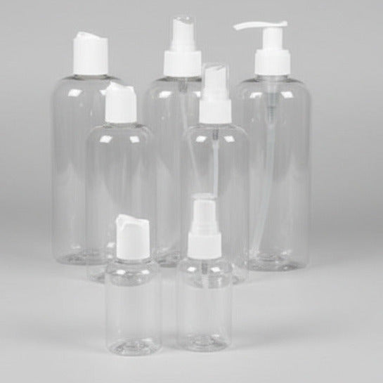 Set of clear plastic bottles with white caps on a grey background
